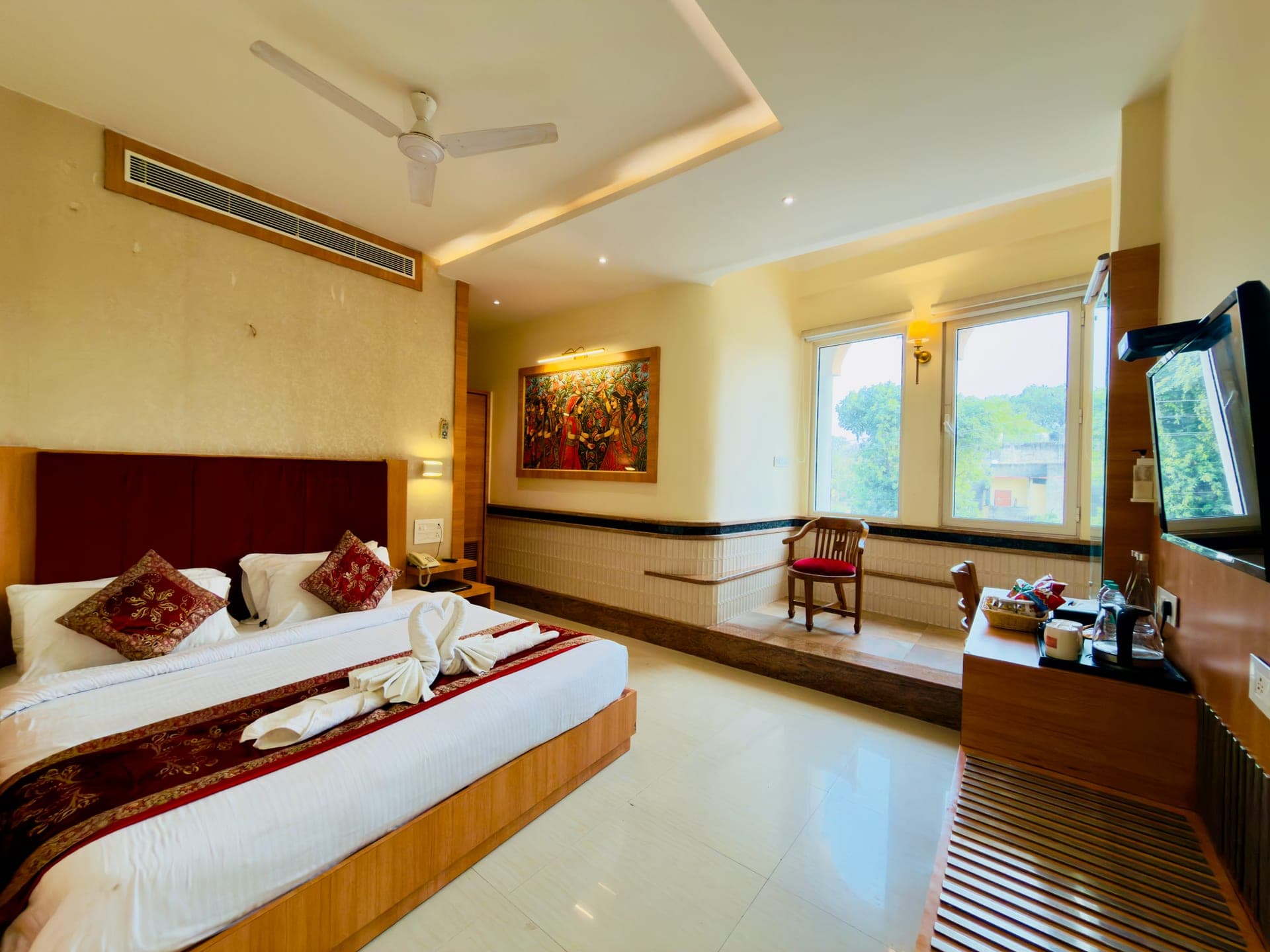 A Hotel Vagmi guest room — warm wood and a made bed by a bright window.