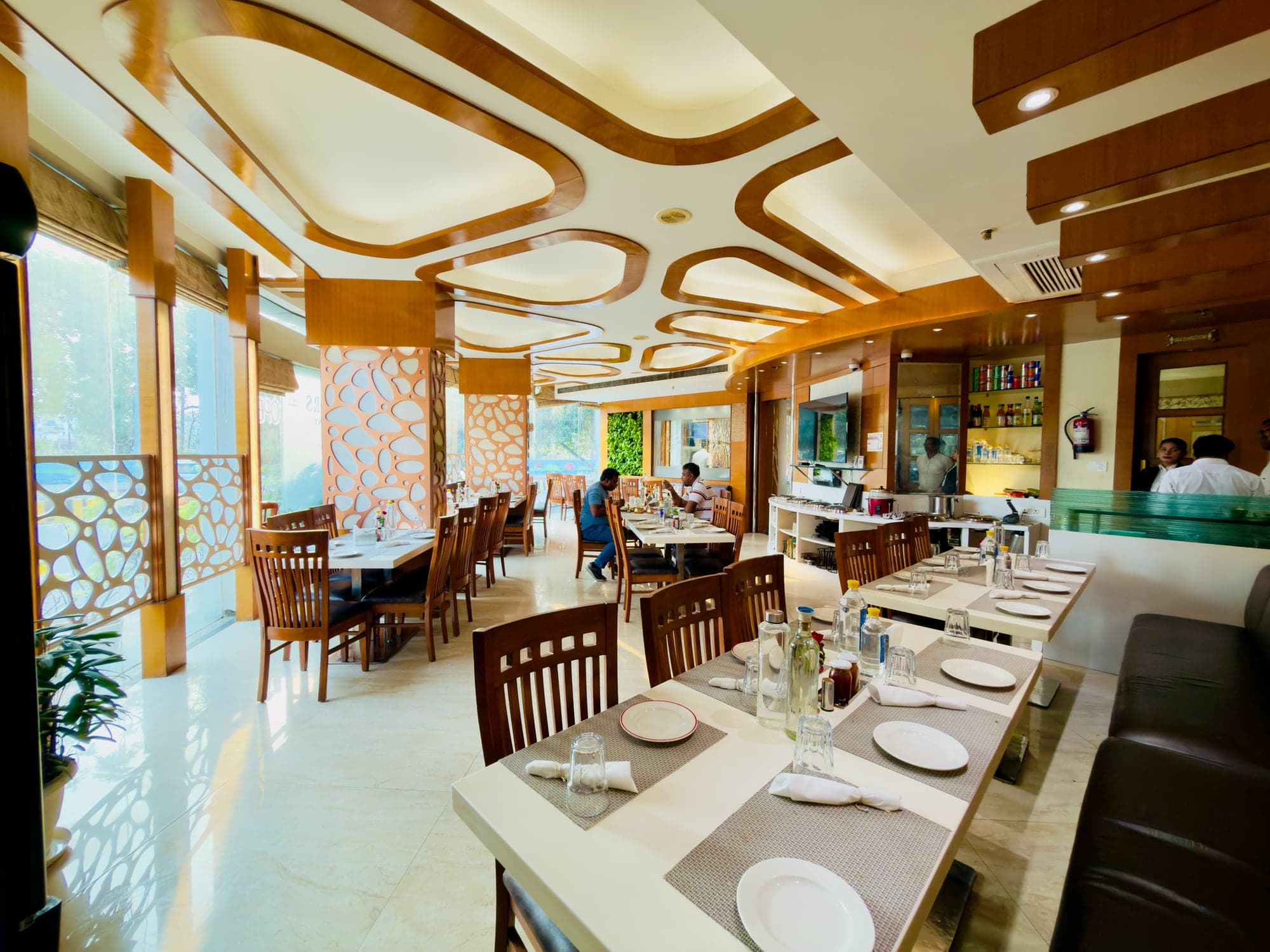 Laid tables at Flavours restaurant — wooden chairs, white runners, the carved ceiling above