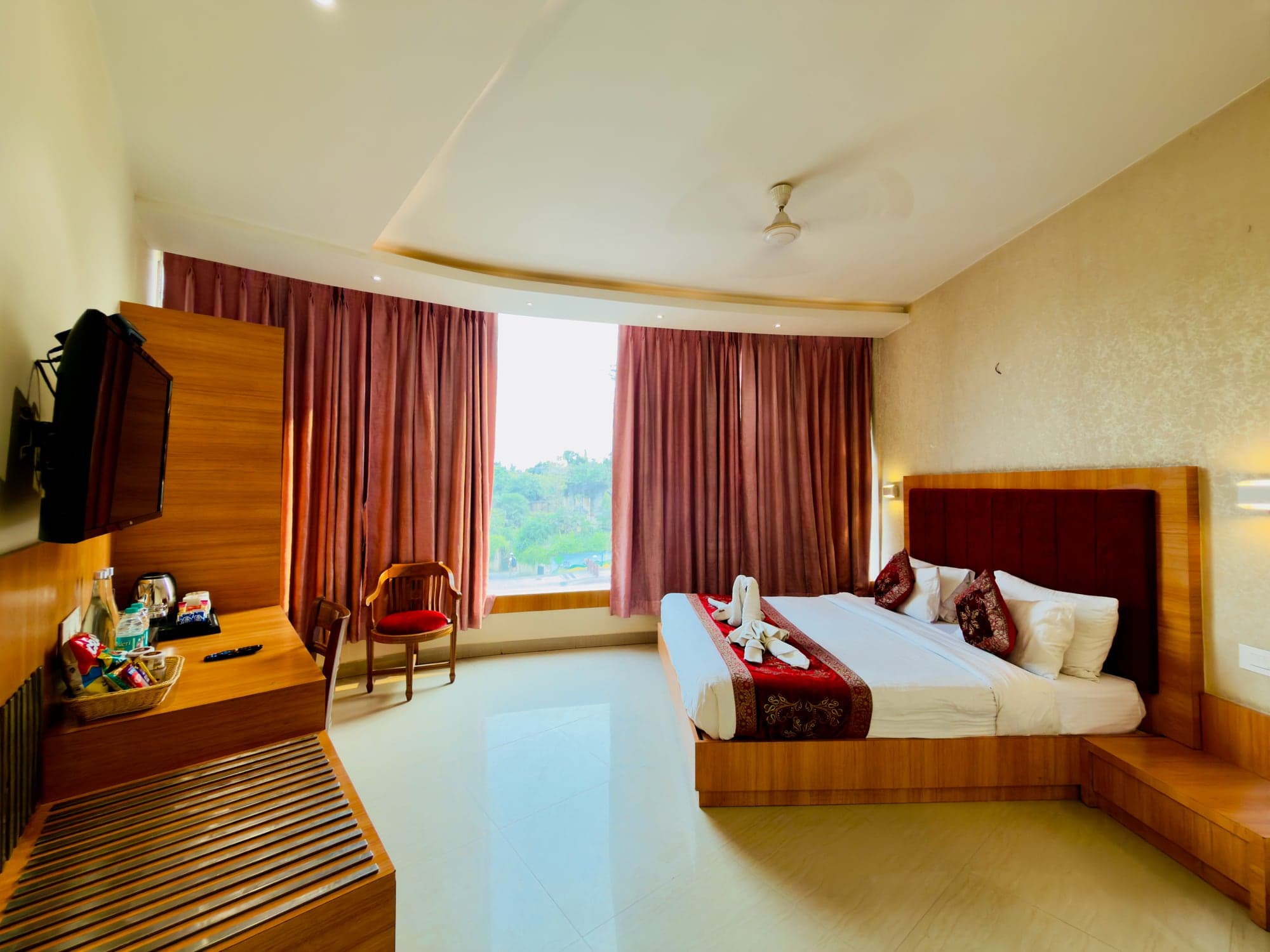 Deluxe room window alcove with reading chair and rose-brown curtains, daylight over the sitting ledge