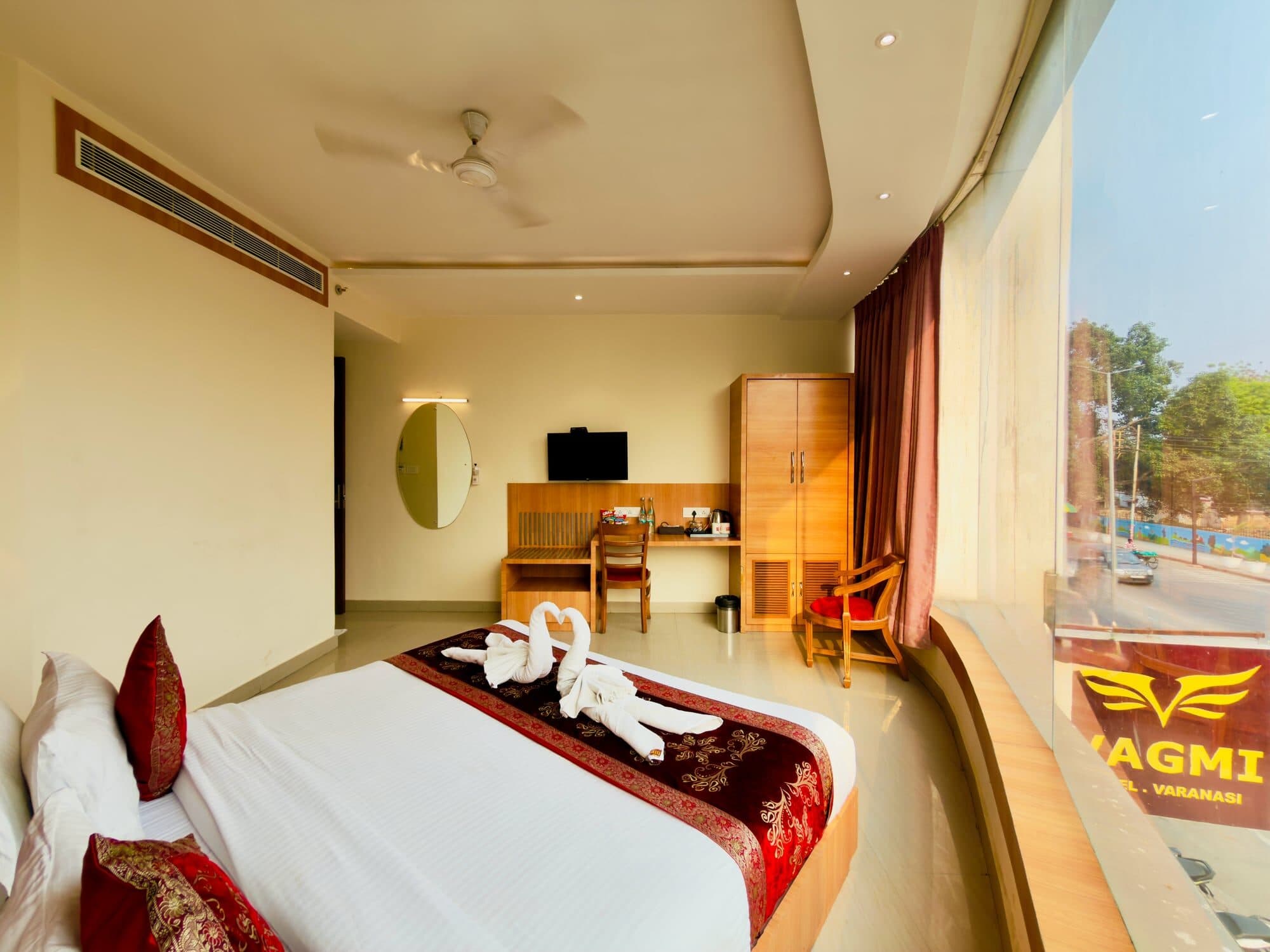 Deluxe room king bed beside the corner picture window, the Vagmi facade sign visible through the glass