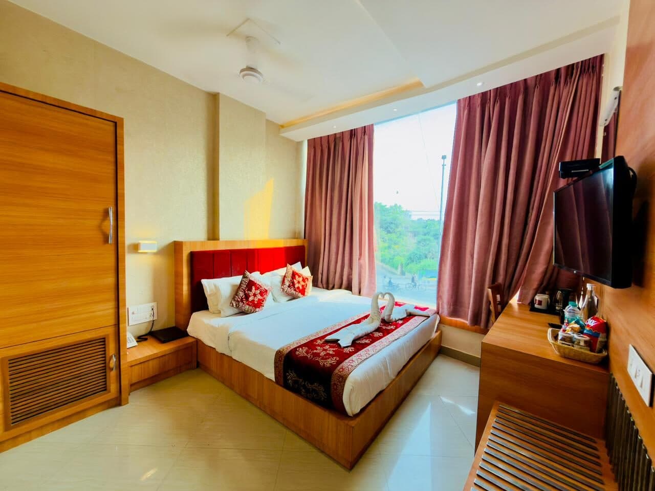 Deluxe room with crimson velvet headboard and towel swans, morning light through the street-side window