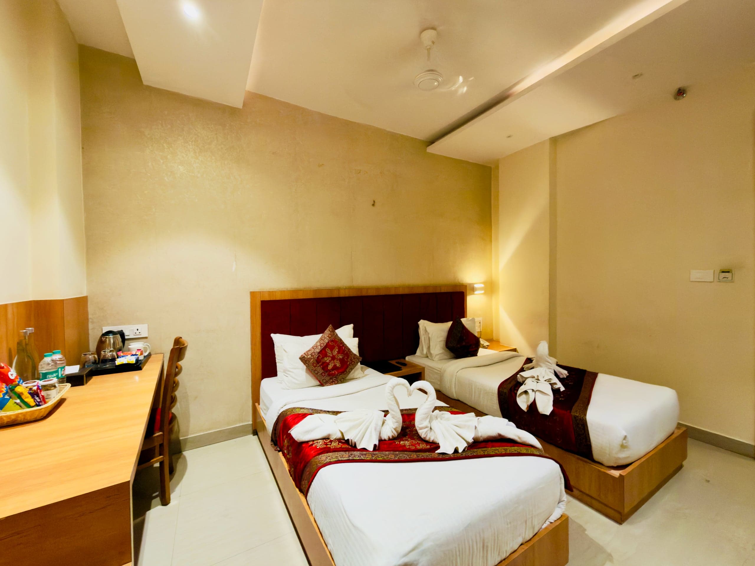 Deluxe Twin room at Hotel Vagmi — two single beds with crimson runners and towel swans