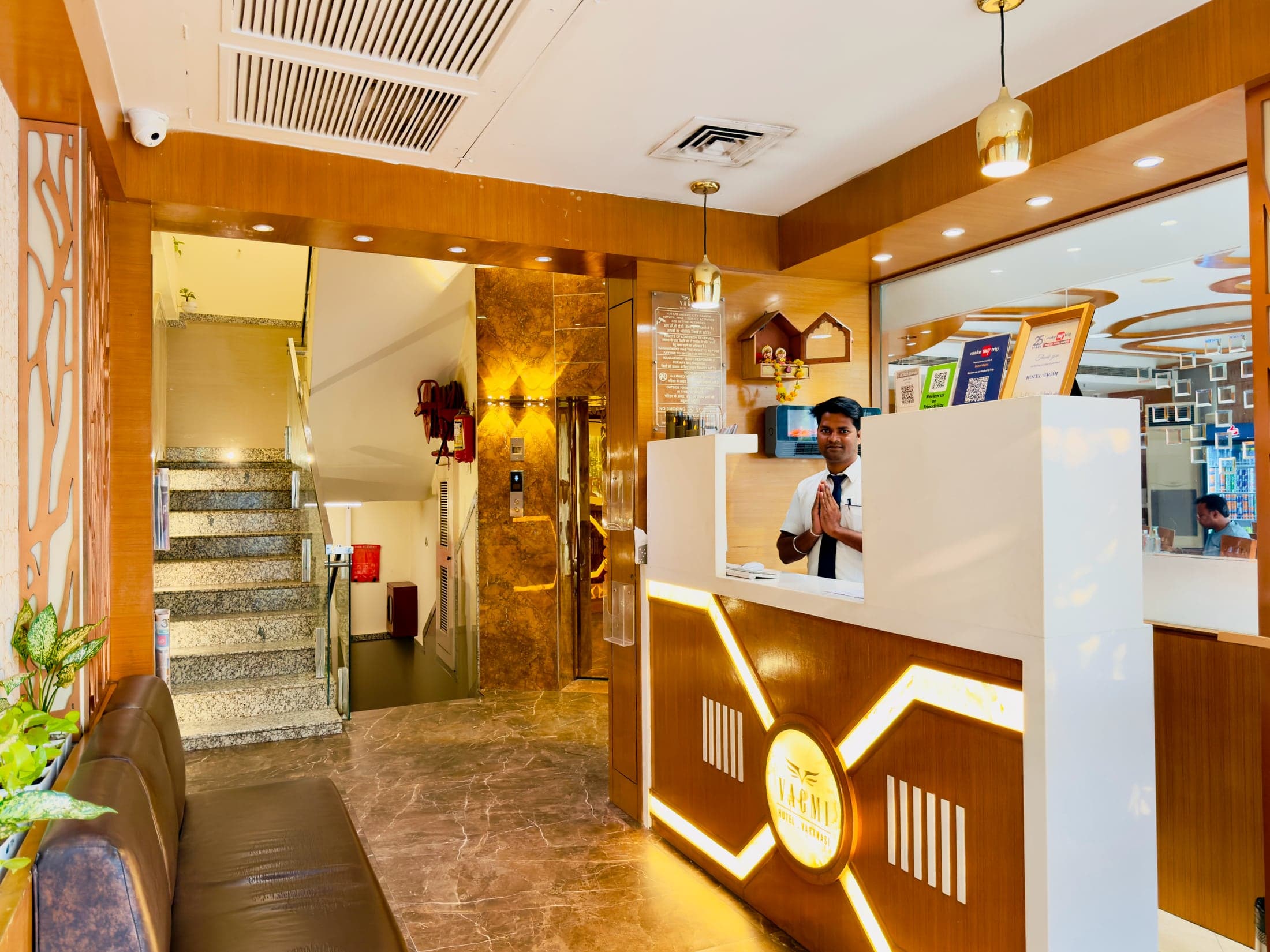 Reception at Hotel Vagmi — a staff member welcoming guests at the brass-lit front desk